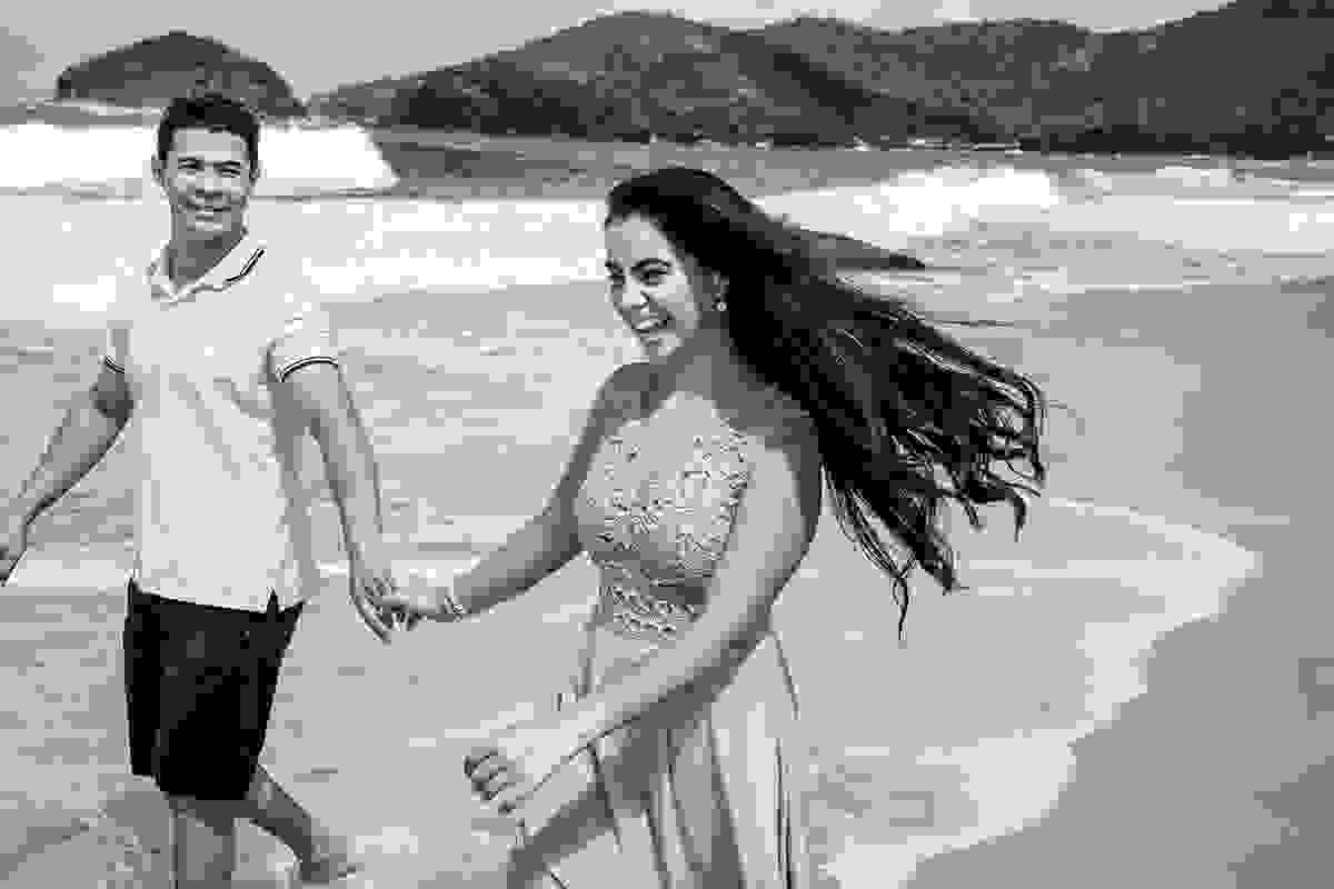casal de noivos caminhando na praia preto e branco
