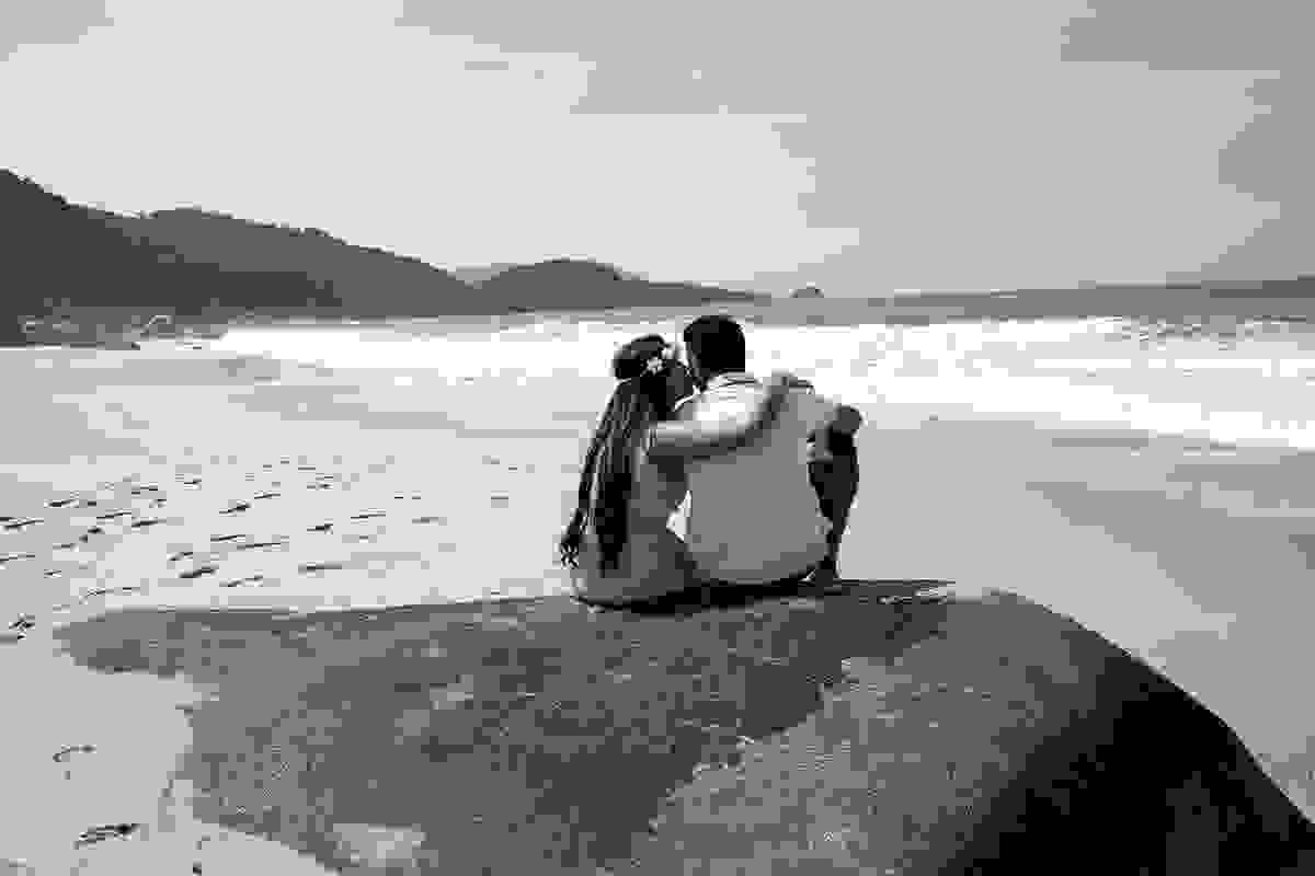 casal de noivos sentados na praia preto e branco