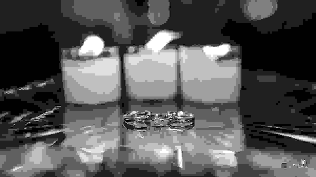 As alianças unidas em frente a velas acesas preparadas para o casamento por Espaço Fotográfico