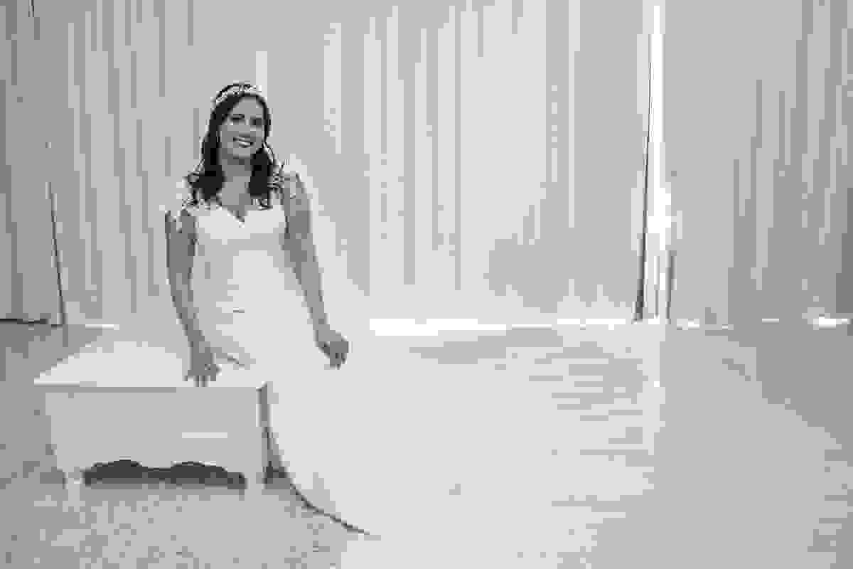 Fotografia da noiva sentada de lado em um puff arrumada pronta para subir ao altar no casamento em cabo frio rio de janeiro