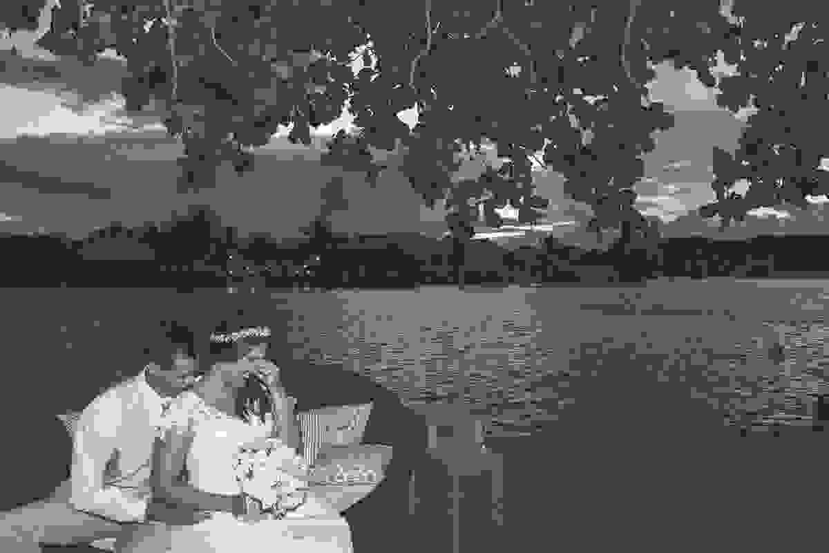Fotografia mostra casal possando para foto sentados no puff a noiva rindo das brincadeiras do fotógrafo e do noivo em fotografia de Casamento em Cabo Frio Rio de Janeiro