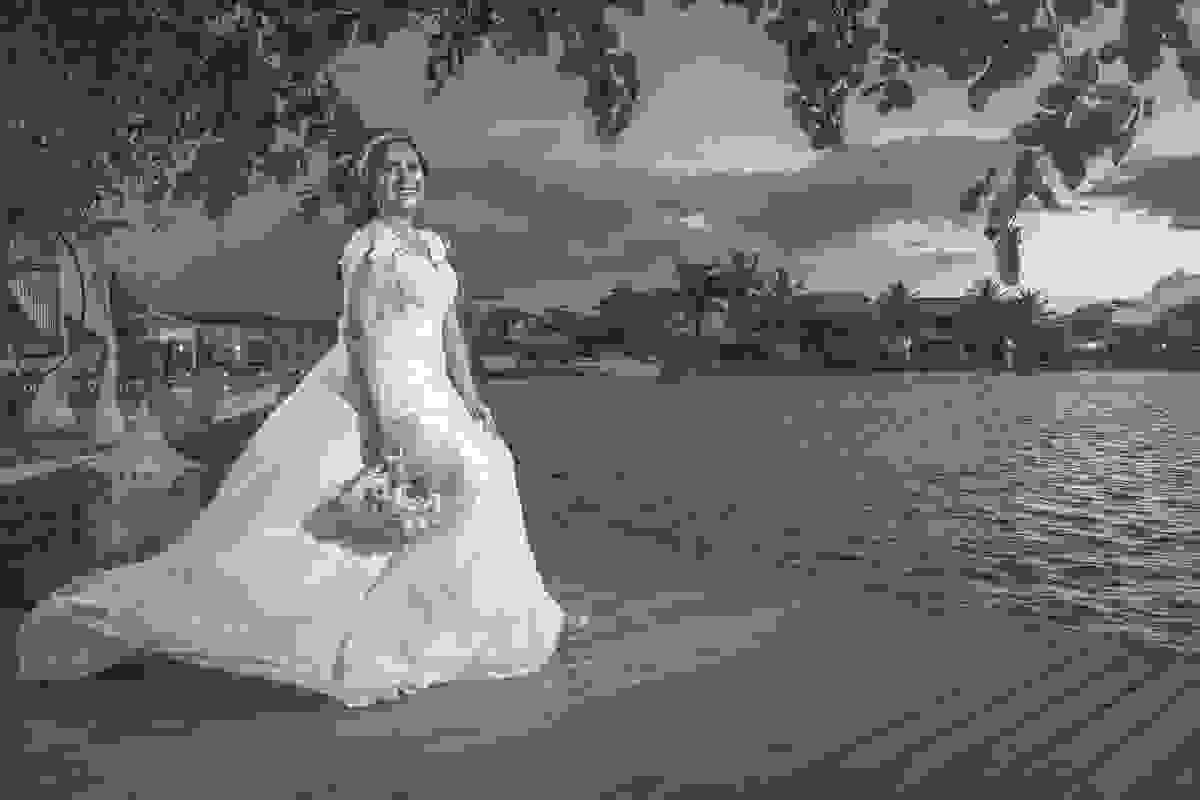 Fotografia da noiva segurando o bouquet ao lado do corpo sentada no deck ao lado do canal de Cabo Frio Rio de Janeiro nesta bela fotografia de casamentp