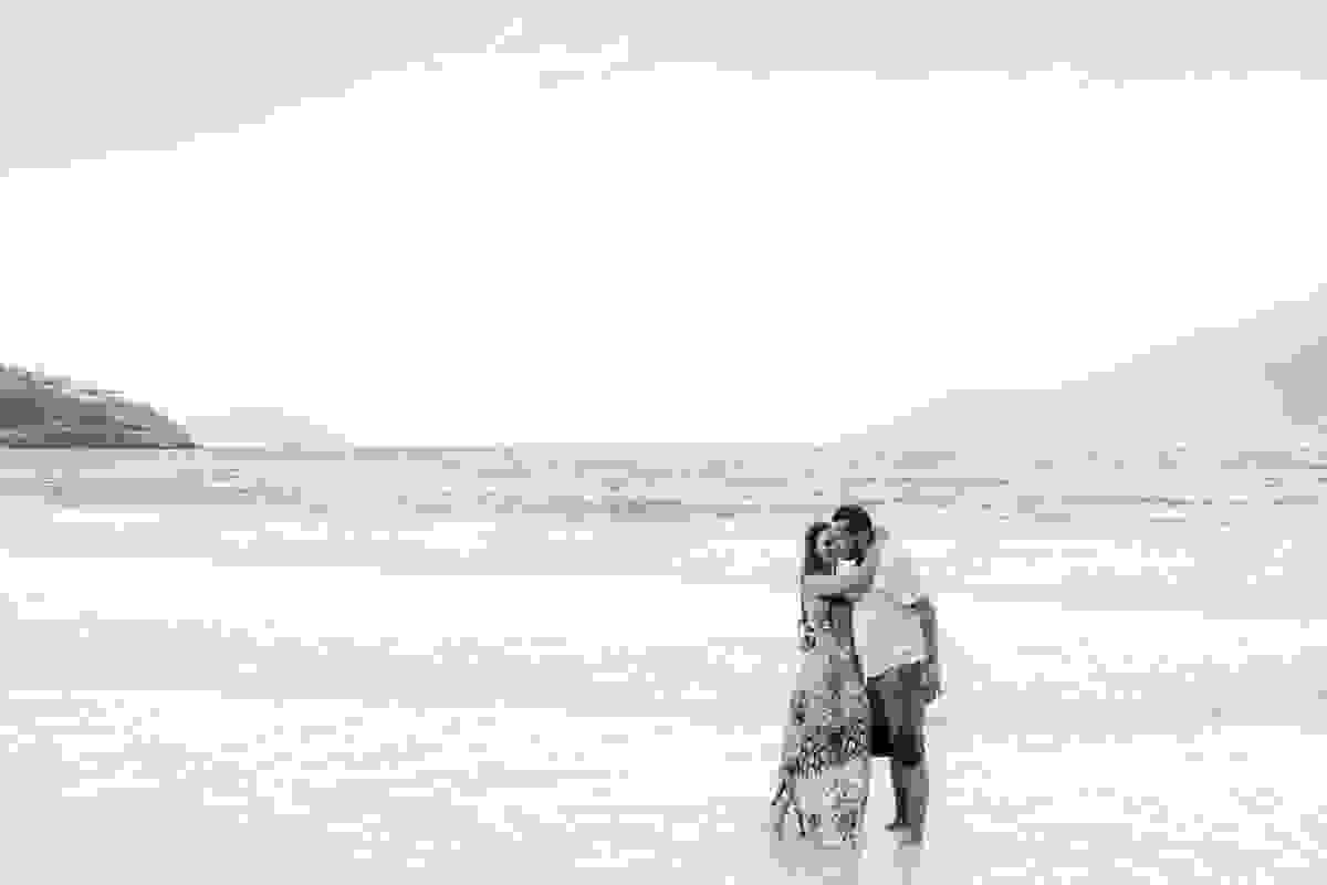 Casal abraçado de frente para a praia de atalaia em arraial do cabo em seu ensaio de pre casamento