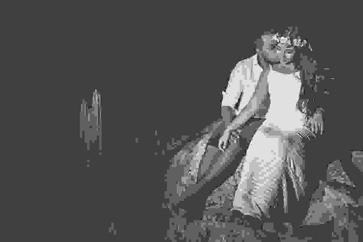Fotografia de ensaio pré casamento feita no alto do atalaia em arraial do cabo mostra casal sentado em uma pedra namorando carinhosamente