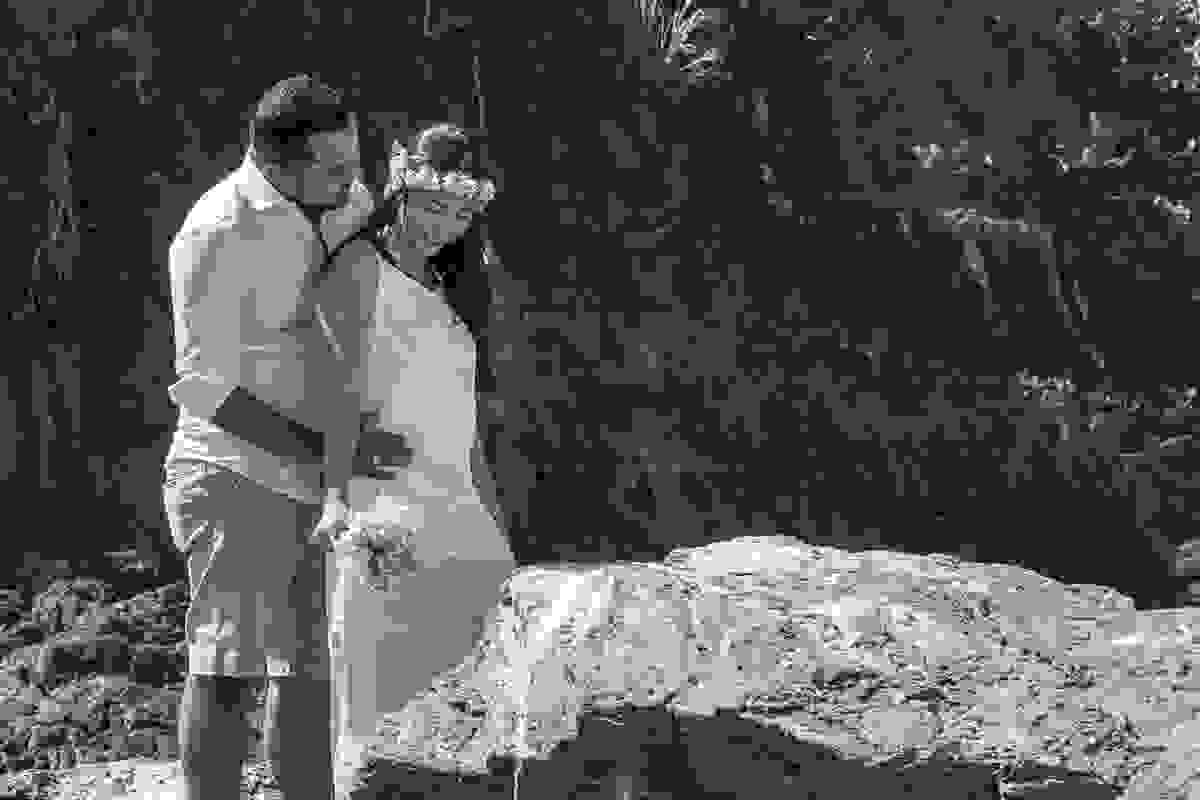 Noivo abraçando a noiva por detras enguanto ela sorri em linda foto na praia de cabo frio rio de janeiro