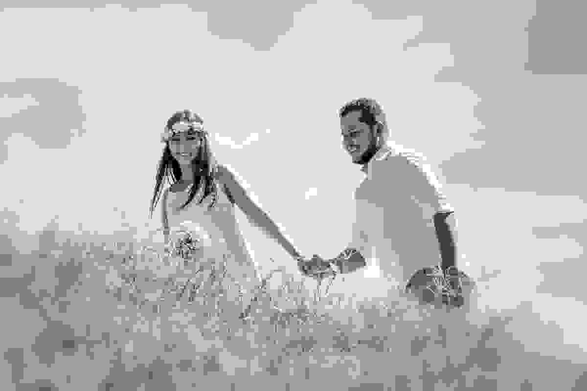 Casal caminha por detras de pequena vegetação enguanto sobe as pedras para fotografar no alto em cabo frio praia do forte