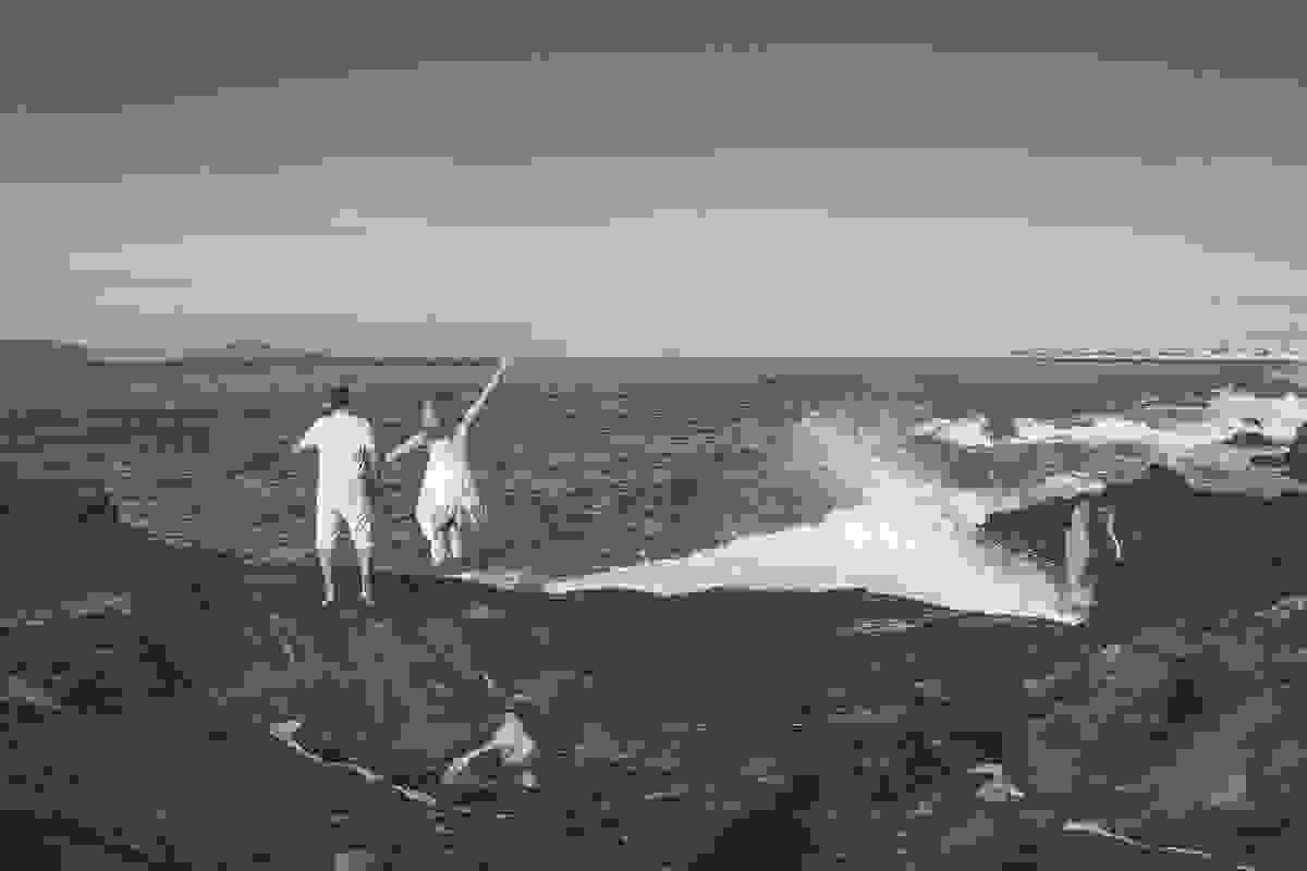 Noiva pula e ergue os braços de frente para o mar em ensaio