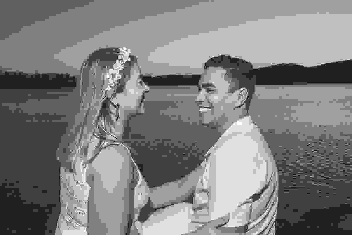 Casal sorrindo em fotografia pré casamento e ao fundo o canal de cabo frio com o nascer do sol