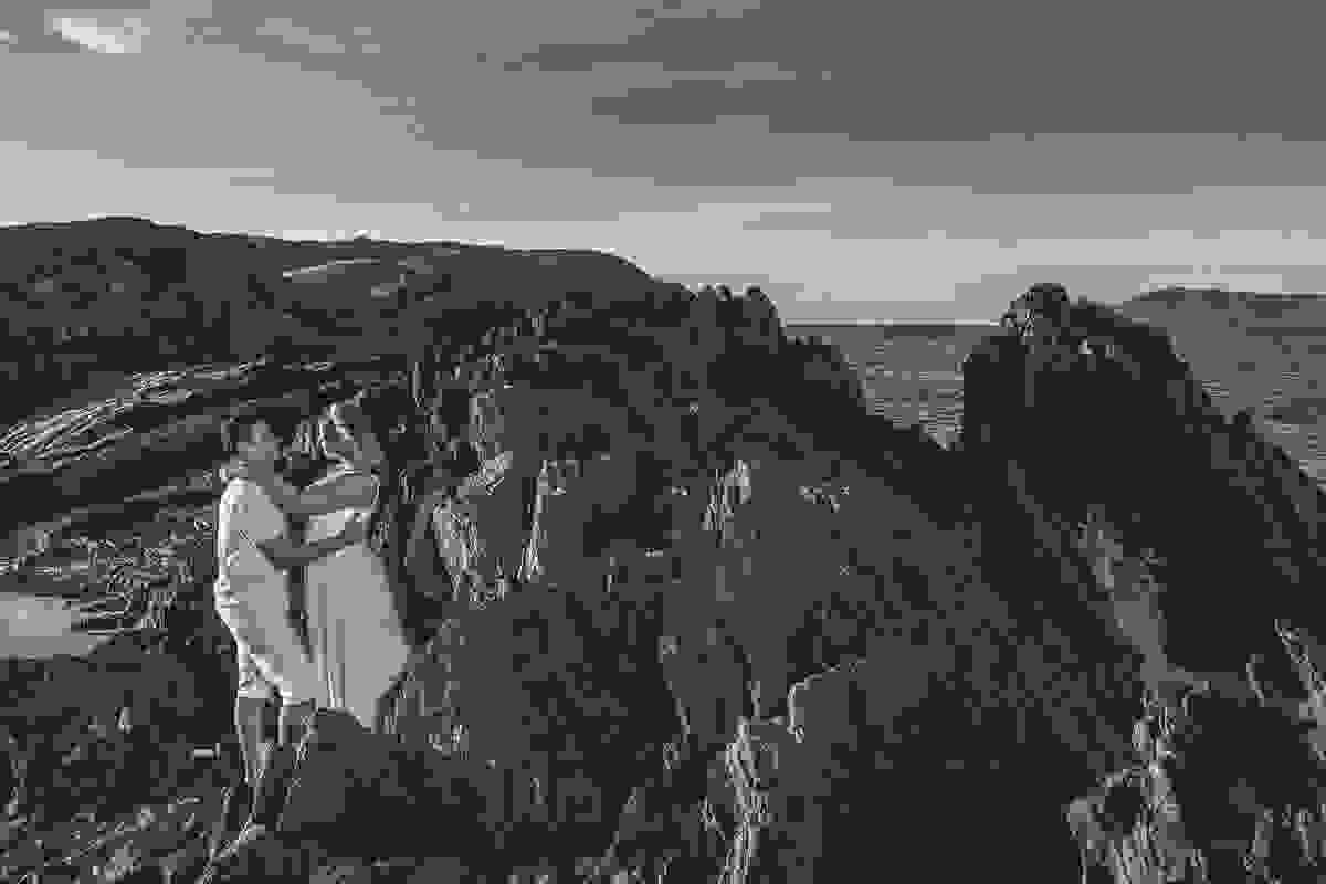 casal ensaio pré casamento foto por entre rochedos próximo ao mar