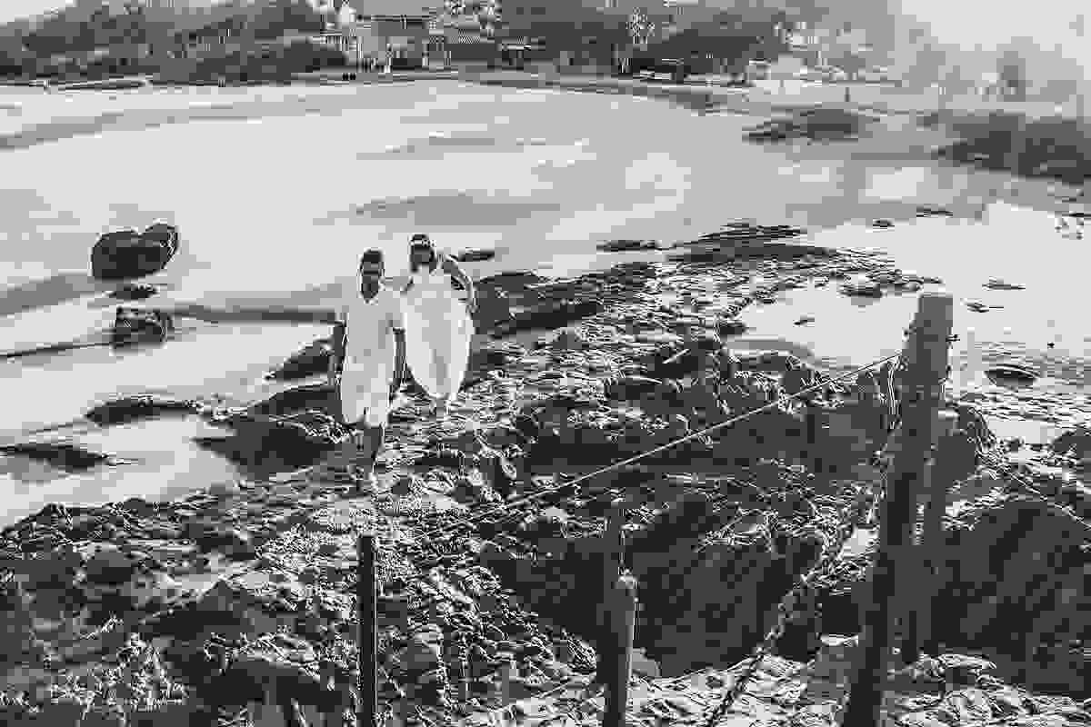 casal caminhando por entre as pedras em praia de cabo frio rio de janeiro