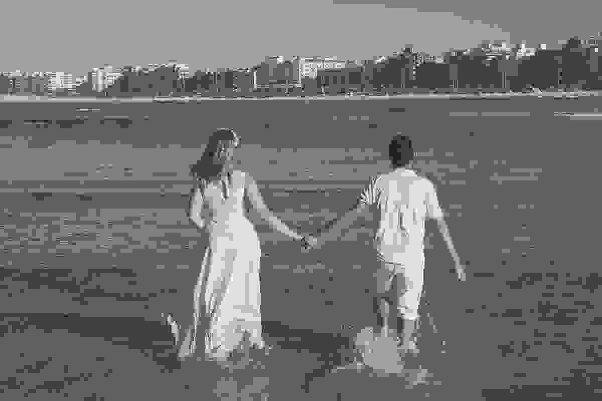 Casal de mãos dadas caminhando para entrar no mar