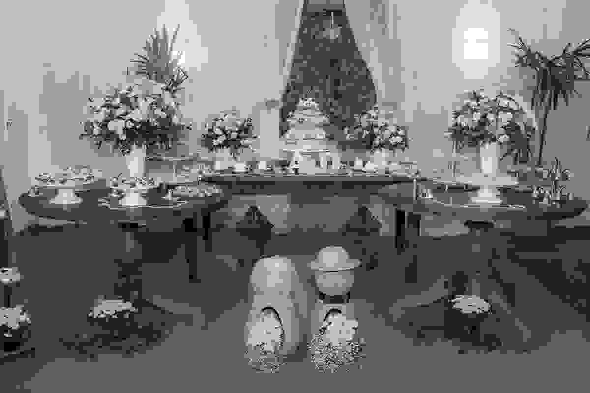 Fotografia da decoração em tons amarelos e verdes do casamento mostrando a mesa do bolo e as mesas larerais