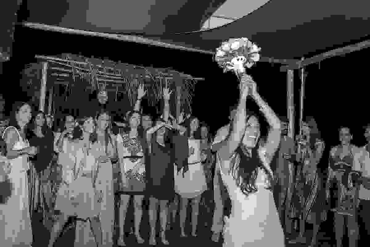 Fotografia mostra a noiva com os braços no alto jogando o bouquet