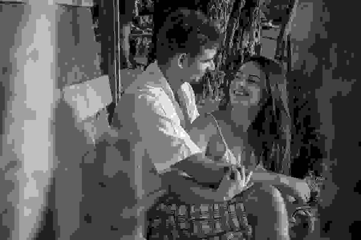 Casal se olha em sessão de fotos do pré casamento sentados na escadinha de acesso ao barco