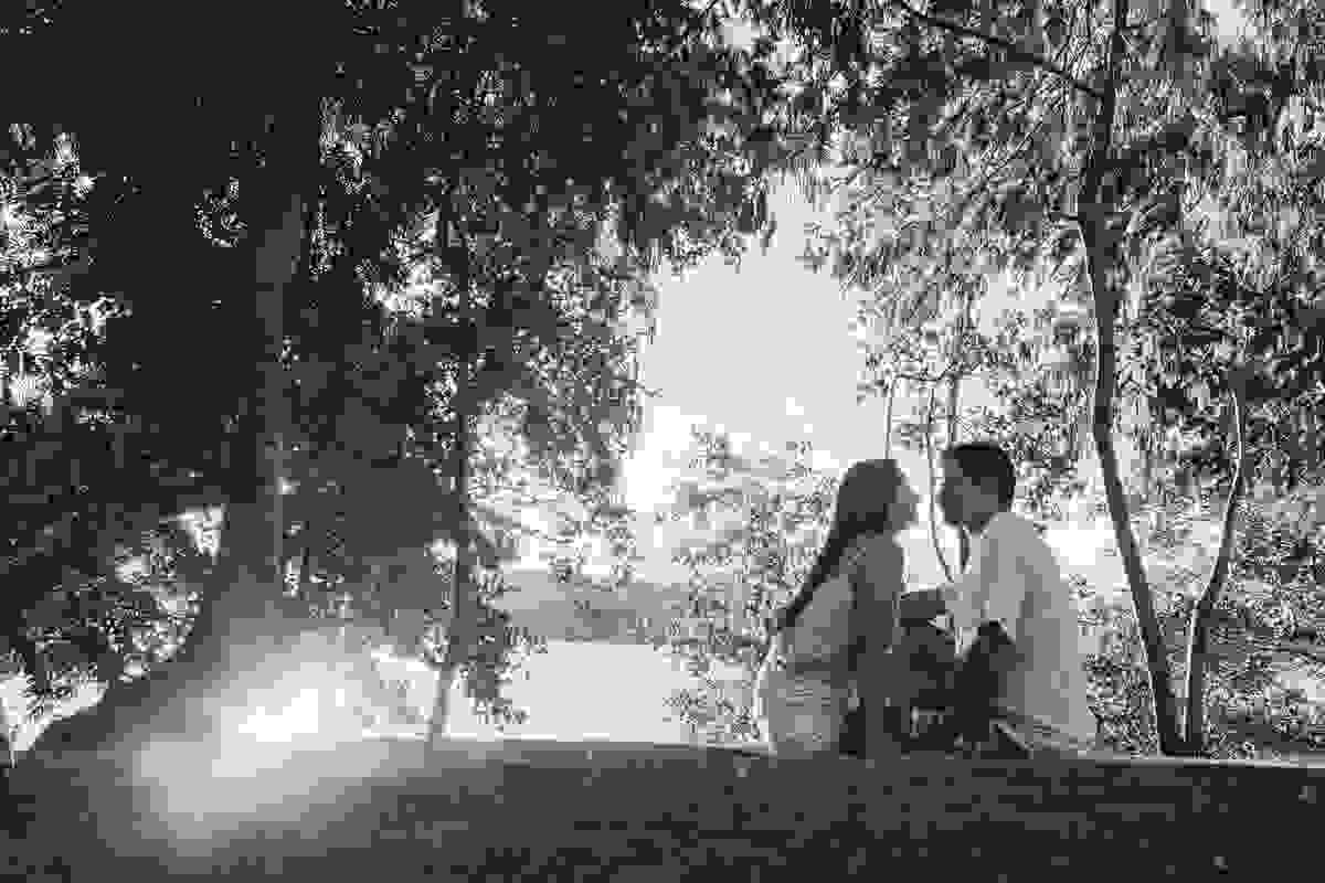 Casal esta sentado no gramado e a fotografia do ensaio de casal esta em preto e branco ao fundo temos o rio são joão