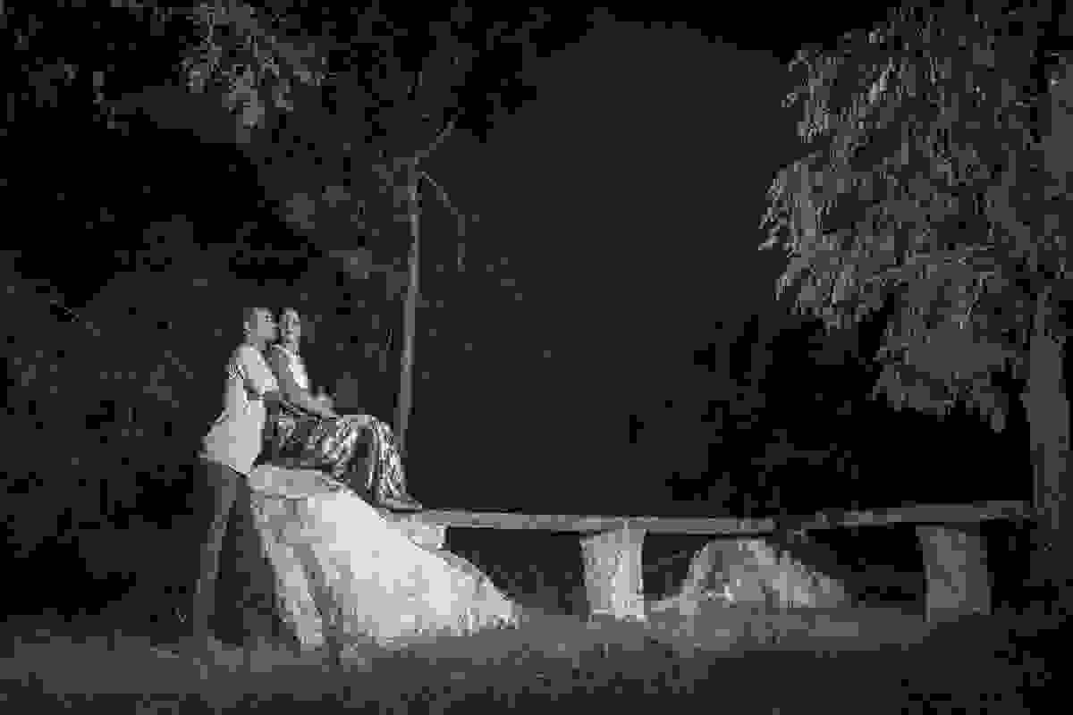 Fotografia de pré casamento já ao cair da noite onde a noiva esta sentada em uma pedra alta e o noiva abraçando ela por traz