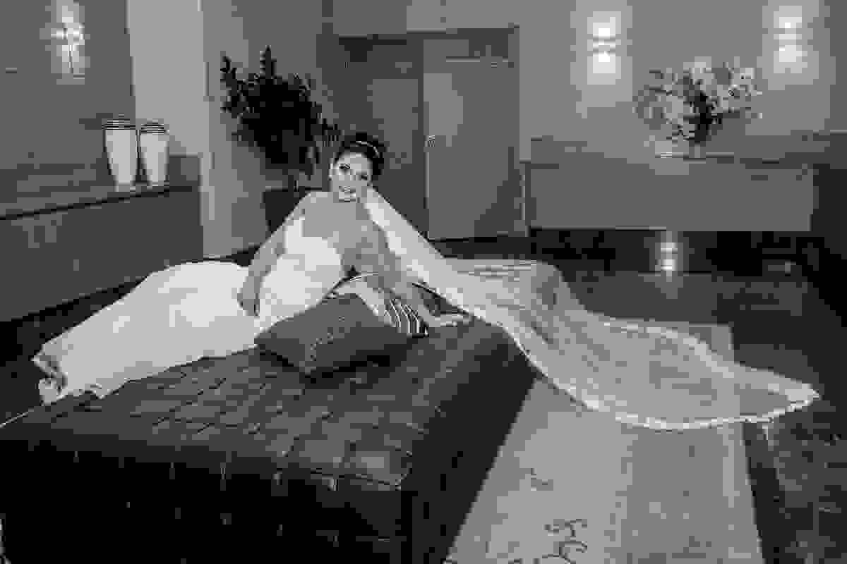 noiva sentada em sofa no hall do hotel posando para a foto mostrando seu belo véu