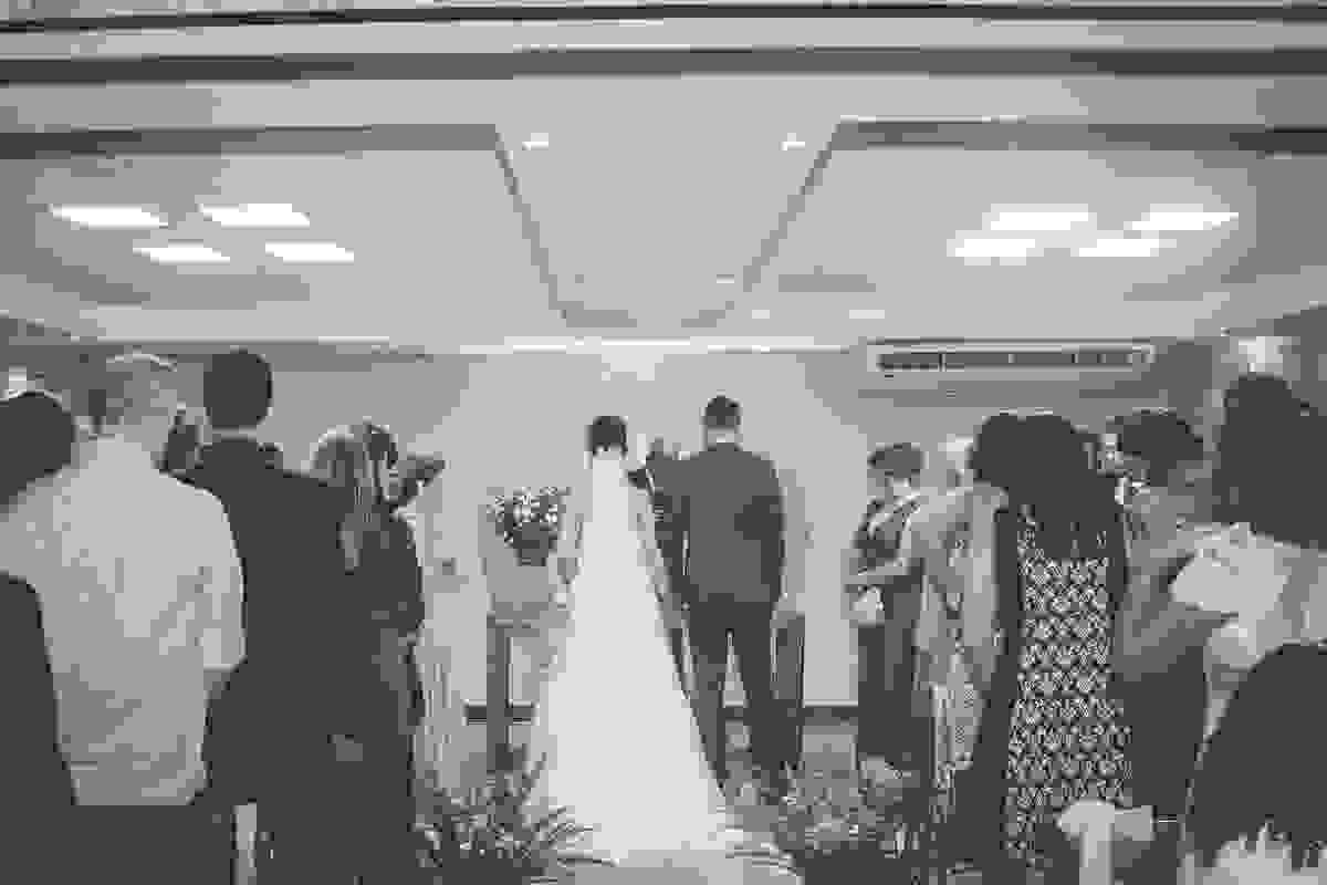 fotografia do casamento em macaé mostra casal de costas e convidados assistindo a cerimonia