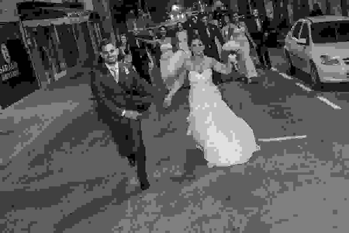 Noivos brincam que estão correndo dos padrinhos em fotografia divertida do casamento