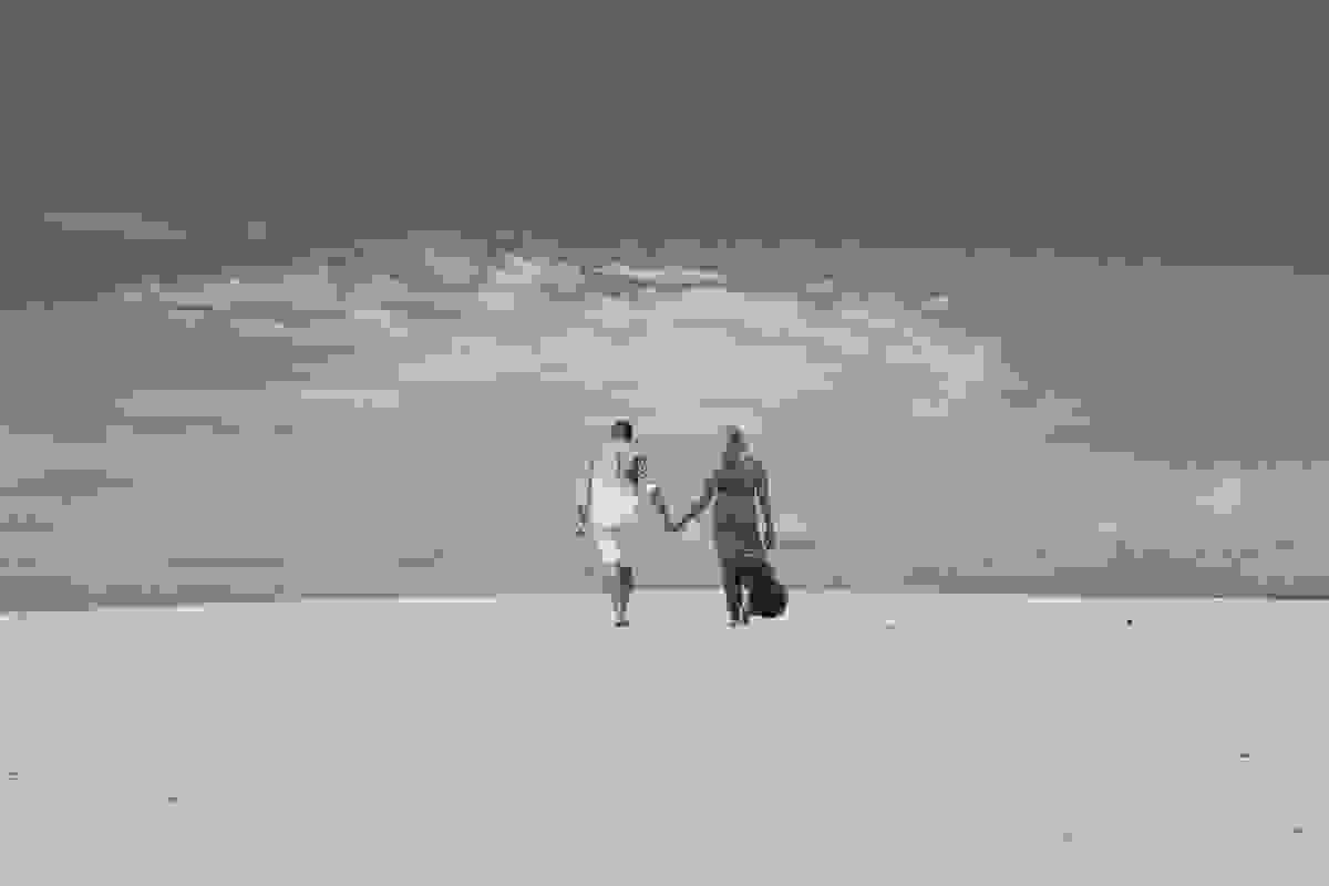 casal caminhando pelas areias da praia e um lindo seu azul durante ensaio pré casamento