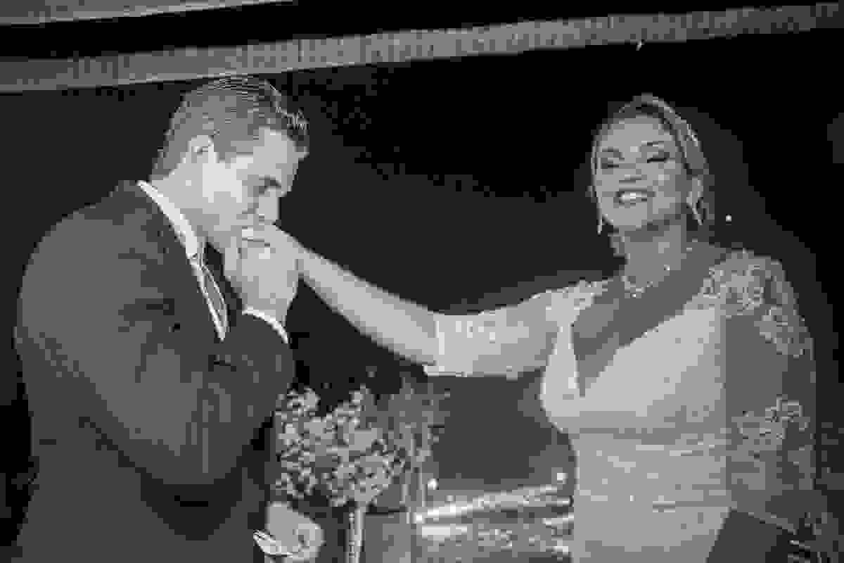 Noivo beija a mão da noiva que sorri feliz durante o casamento em macaé