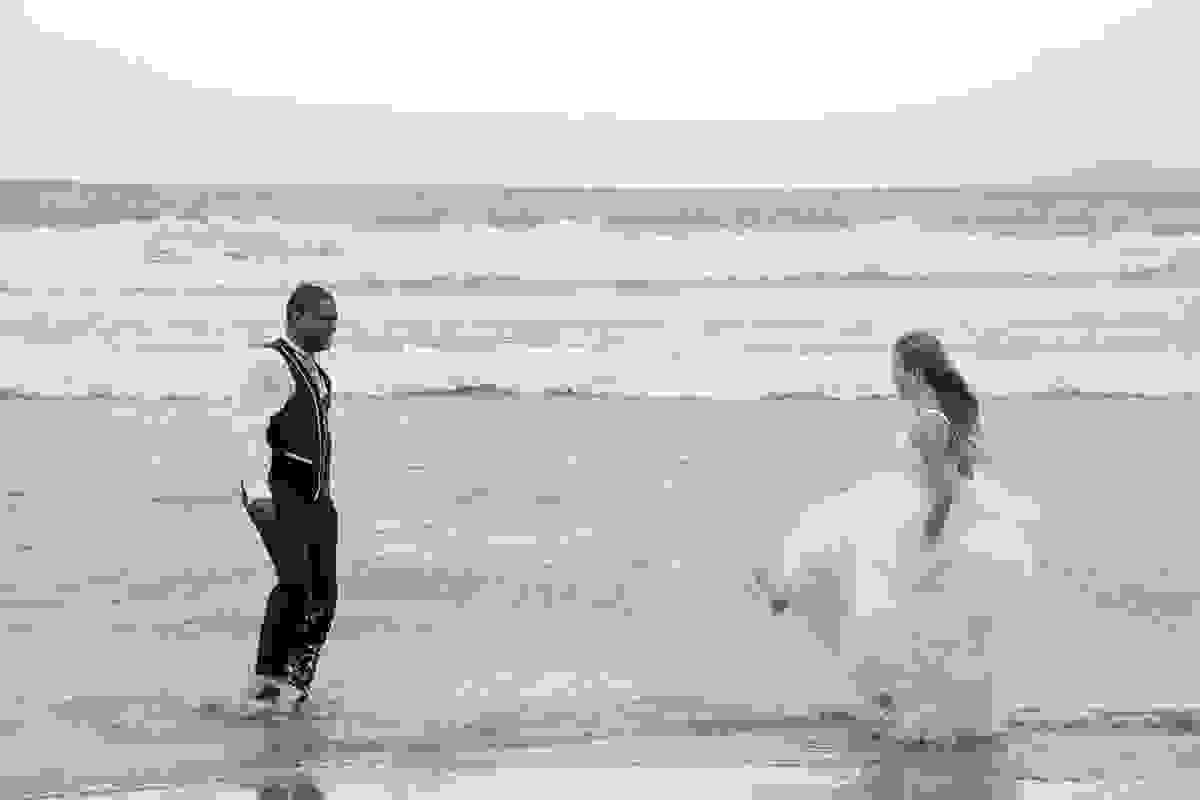 Noiva joga agua com os pés tentando acertar o noivo casal se diverte em ensaio Trahs The Dress em búzios
