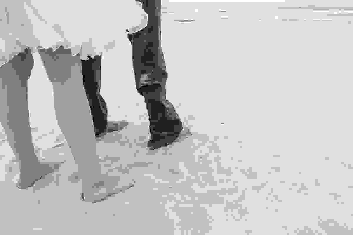 Fotografia preto e branco mostra os pés do casal nas areias da praia de geribar
