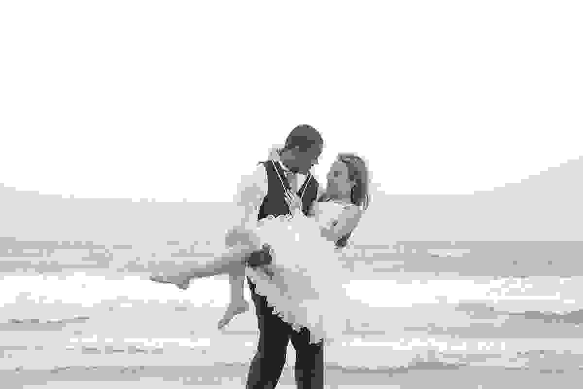 Noivo gira noiva no colo em cena romantica de fotografia preto e branco na praia de geribar em armação dos búzios