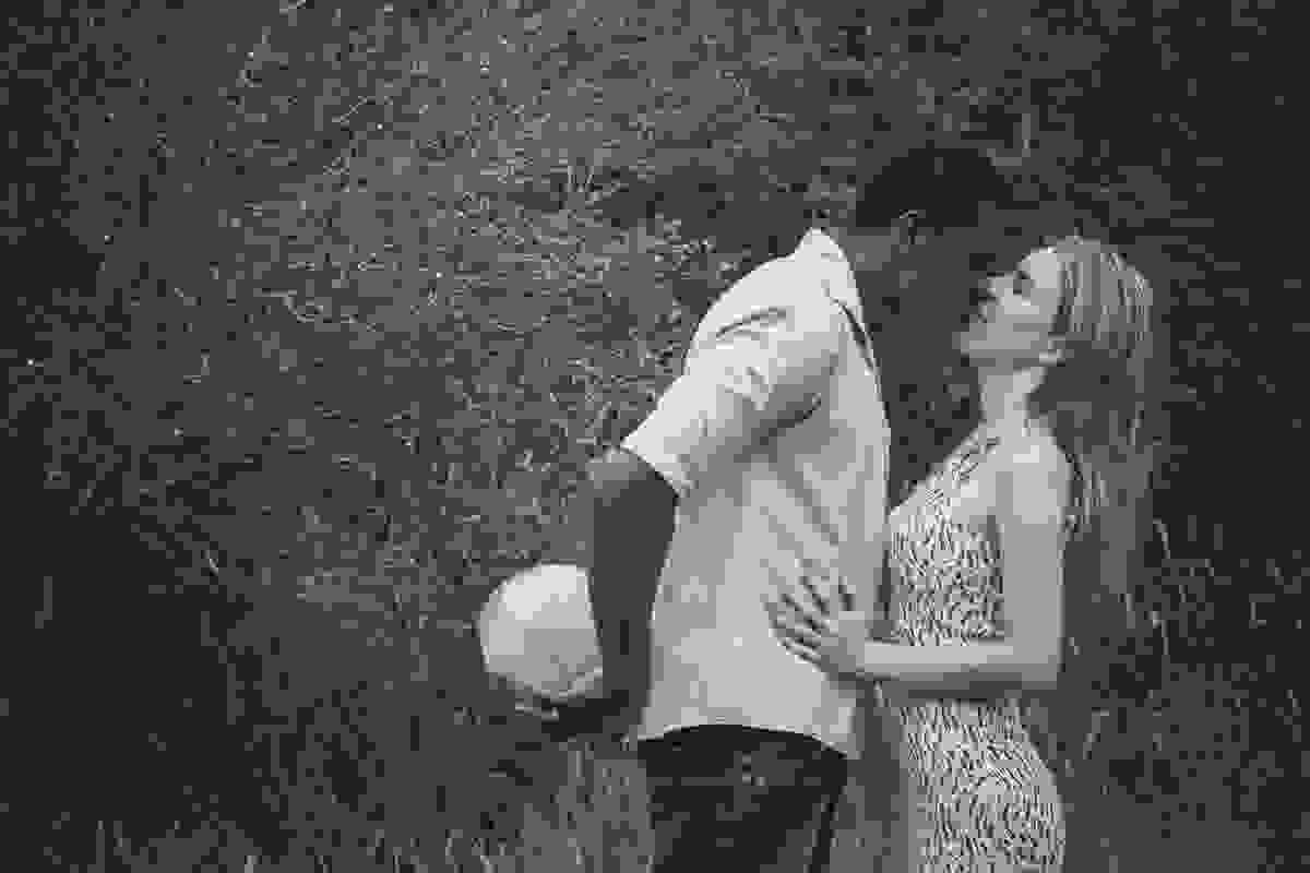noivo esconde uma bola atras das costas enquanto beija a noiva em brincadeira para fotografia do ensaio pré casamento em rio das ostras