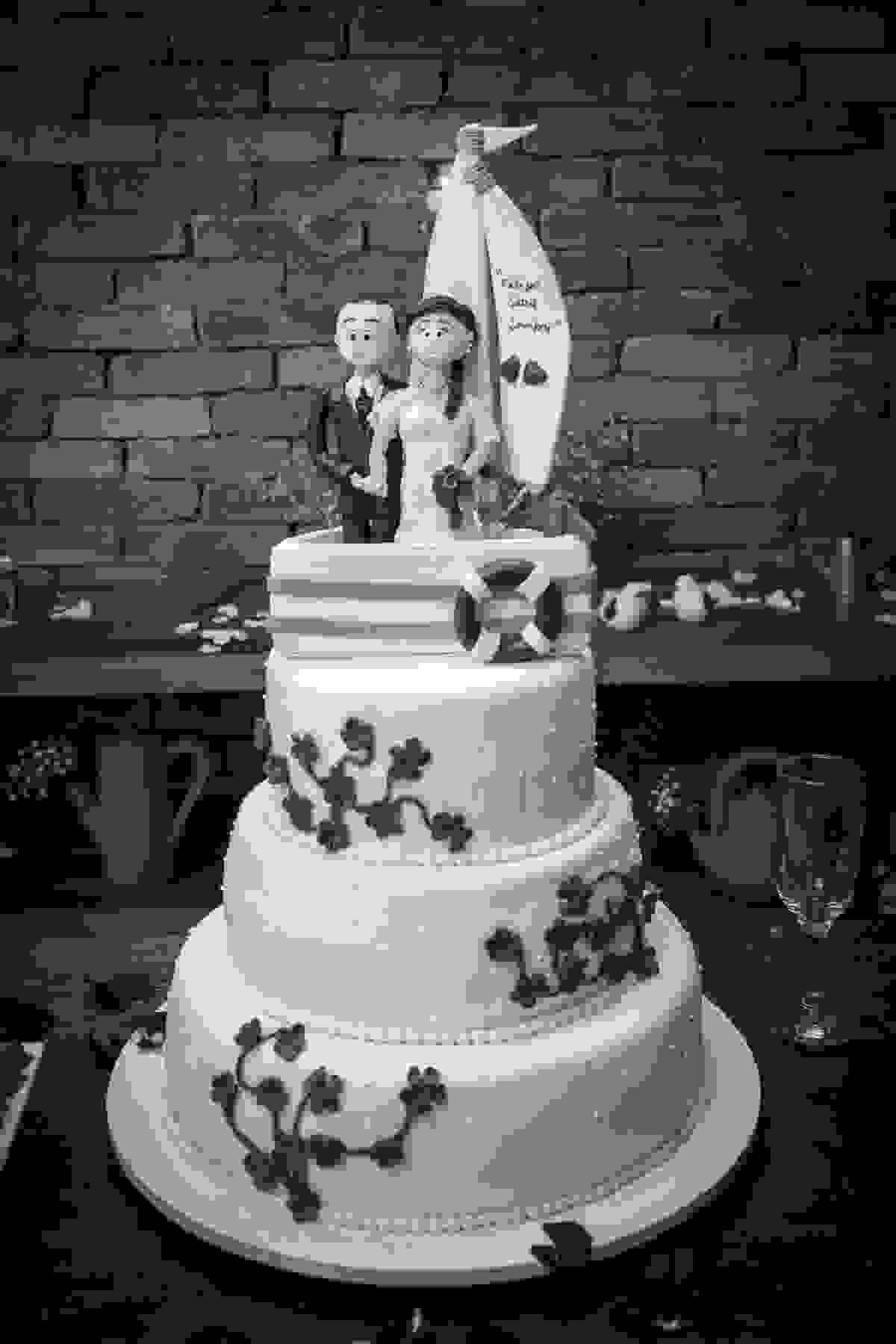Bolo do casamento com noivinhos no topo ele de terno ela de noiva e um barco a vela atraz casamento em botafogo rio de janeiro