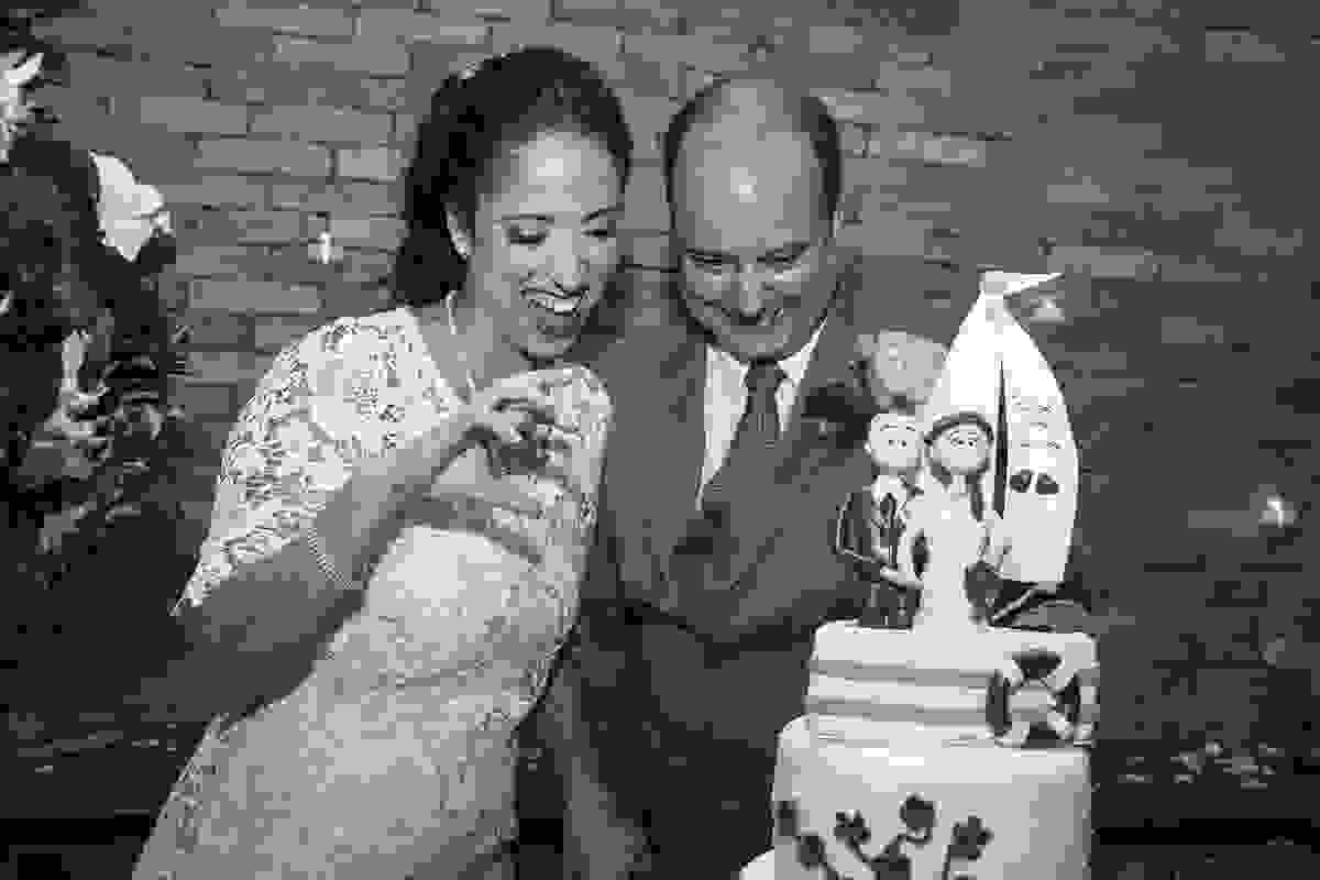 Fotografia do casal de noivos brincando em devorar obolo do casamento