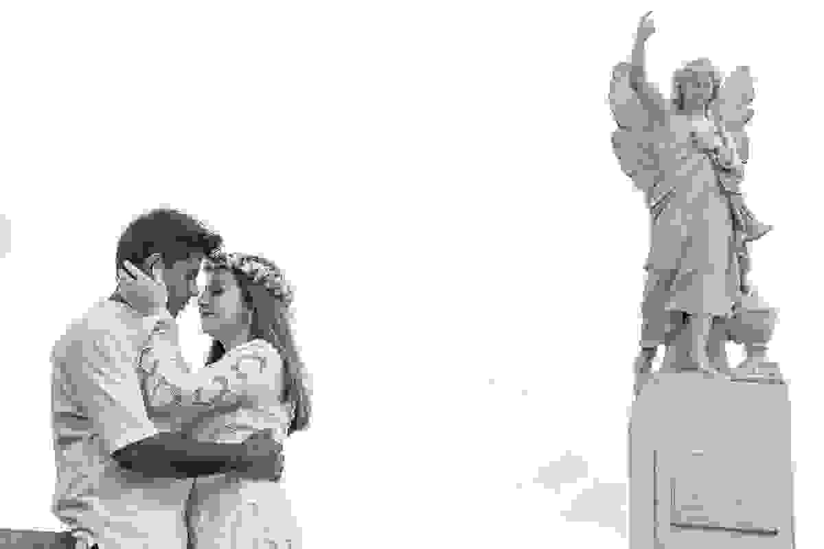 casal posa ao lado de estátua de anjo em fotografia de ensaio pós casamento em Armação dos Búzios Rio de Janeiro