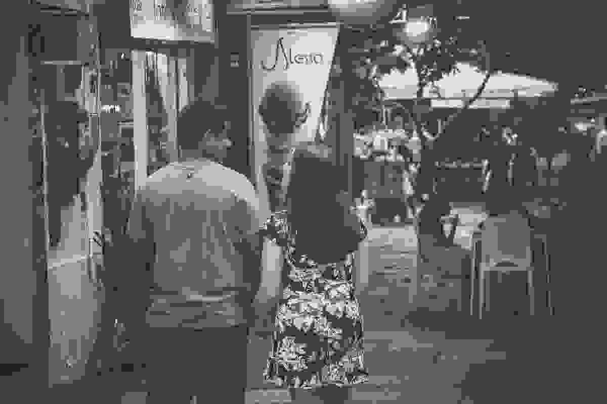 Fotografia em preto e branco de ensaio pós casamento em Armação dos Búzios mnostra casal andando pela Rua das Pedras