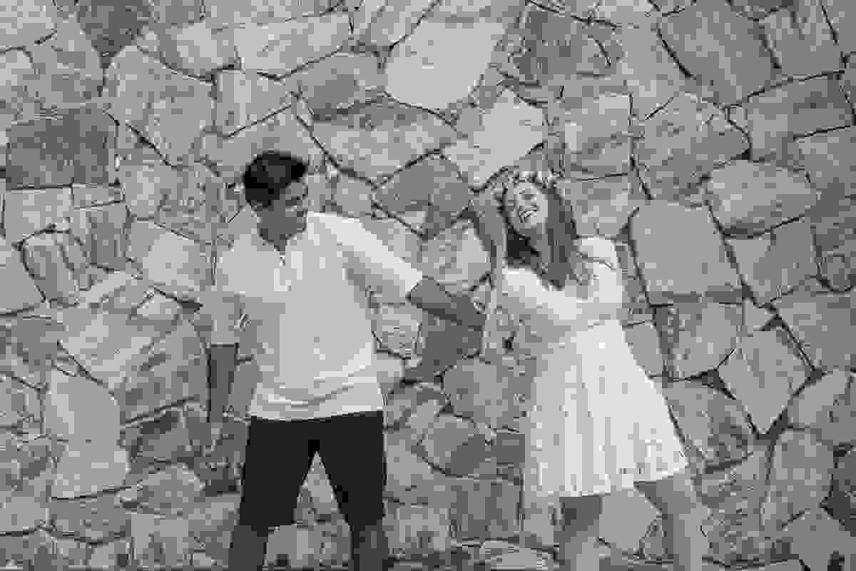 casal brinca diante de um muro de pedras em ensaio de casal em búzios rio de janeiro