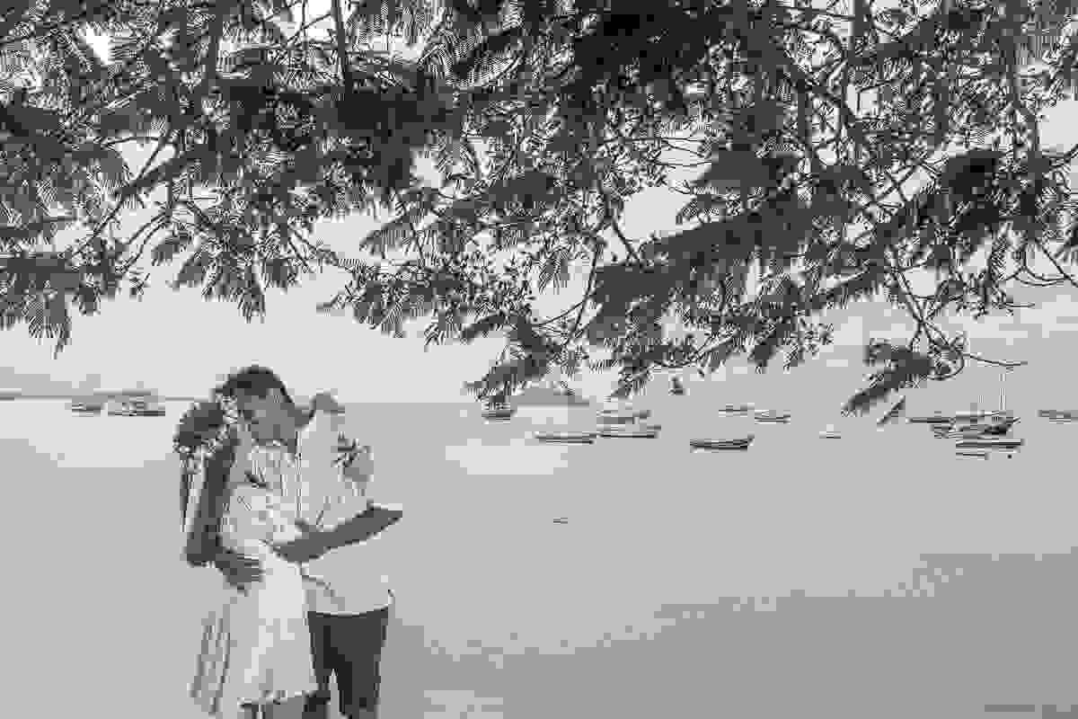 Casal abraçado em foto preto e branco debaixo de uma arvore na praia da armação em búzios durante ensaio fotográfico