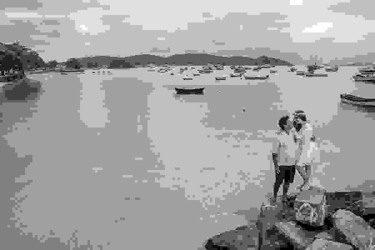 fotografia de casamento em armação dos búzios mostra casam em cima de uma pedra e ao fundo a praia da armação