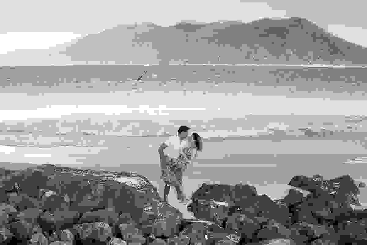 Foto de Casal na praia de arraial do cabo rio de janeiro ele esta segurando a perna dela enguanto se olham