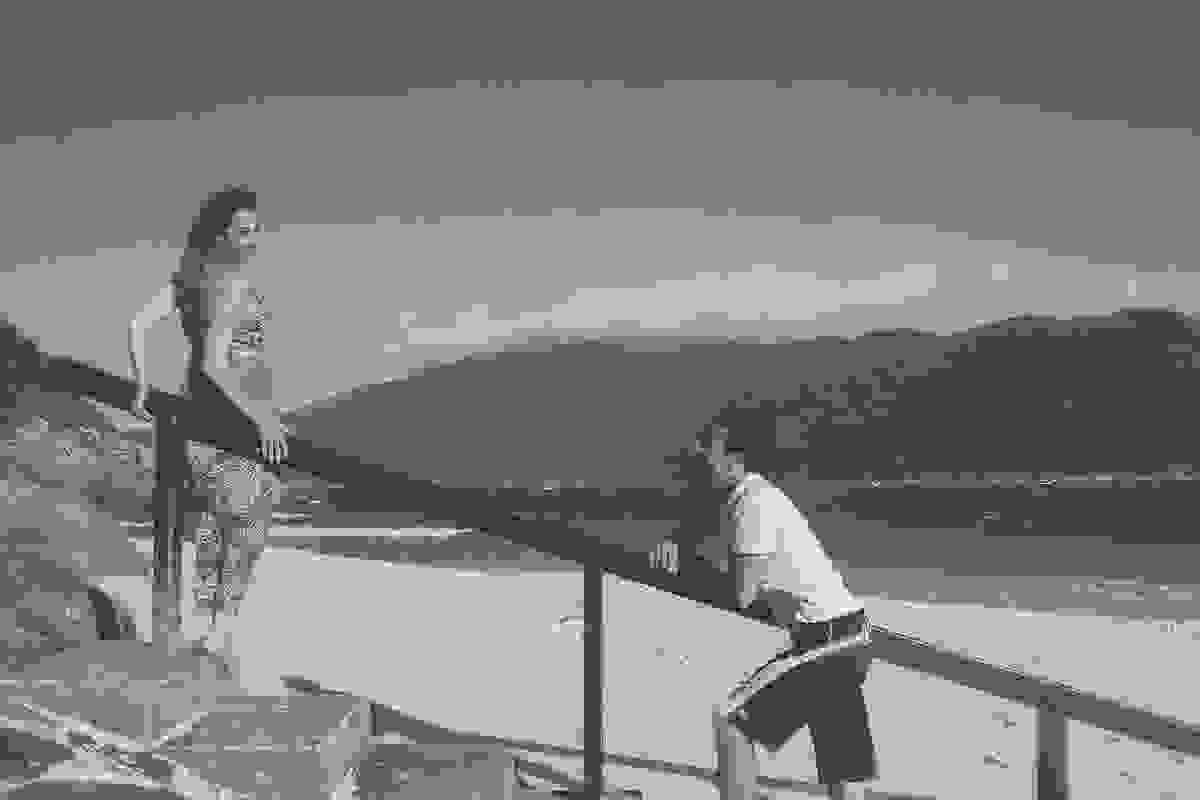 casal esta em uma escada de frente para o mar do atalaia em arraial do cabo rio de janeiro