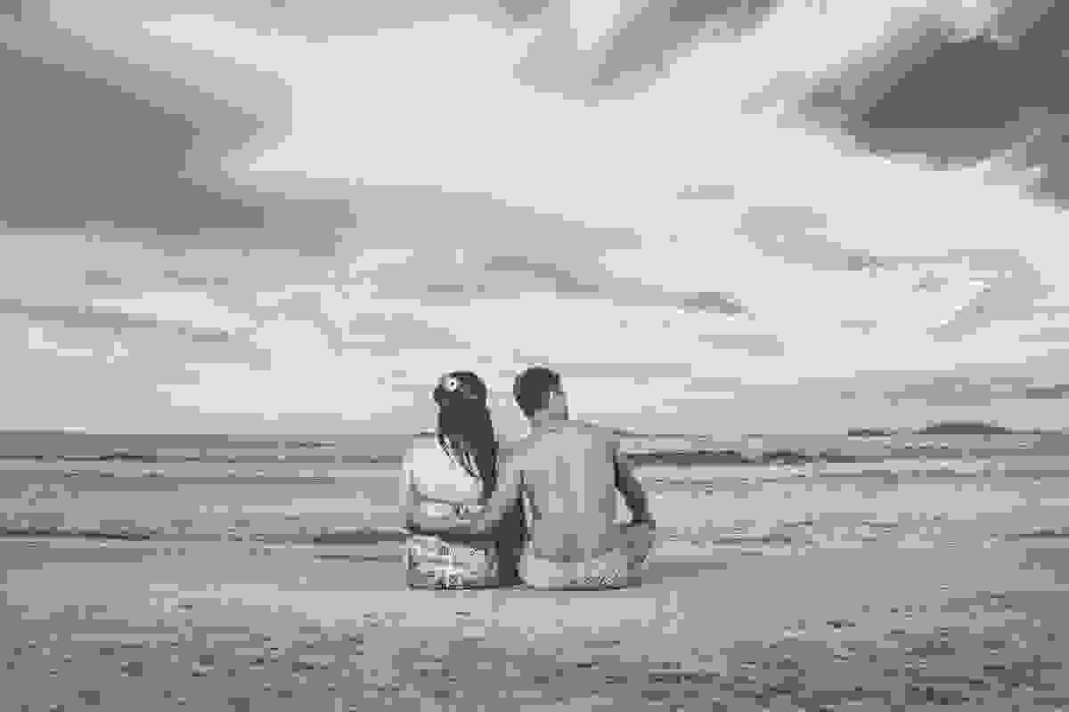 casal sentado de frente para o mar da praia de geribar em búzios rio de janeiro durante o ensaio pré casamento