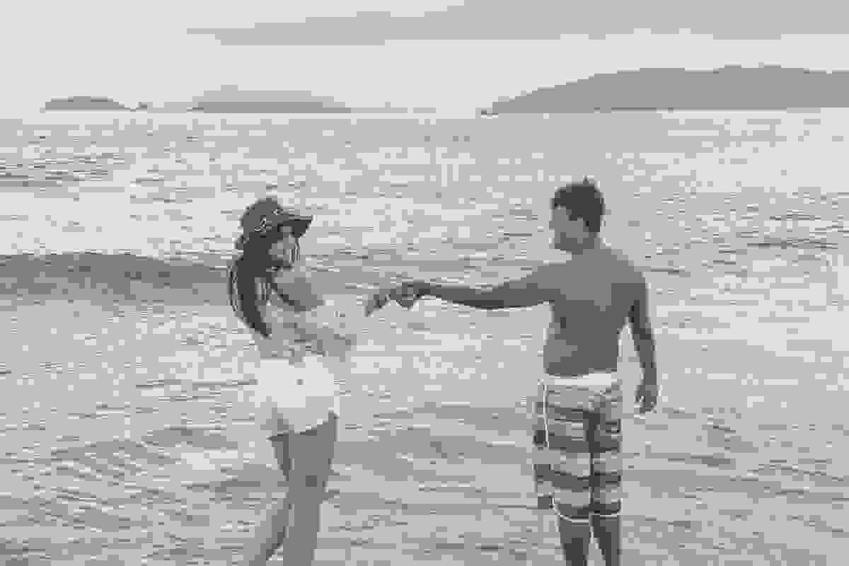 casal ele segurnado a mão dela e ela fazaendo charme junto ao mar da praia de geribar em búzios rio de janeiro