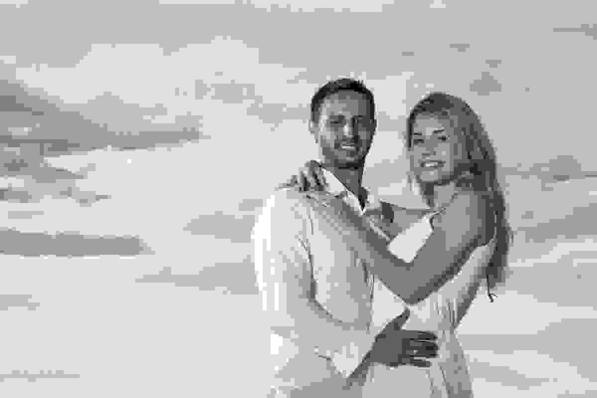retrato do casal olhando para a camera e ao fundo o ceu azul da cidade de cabo frio no rio de janeiro