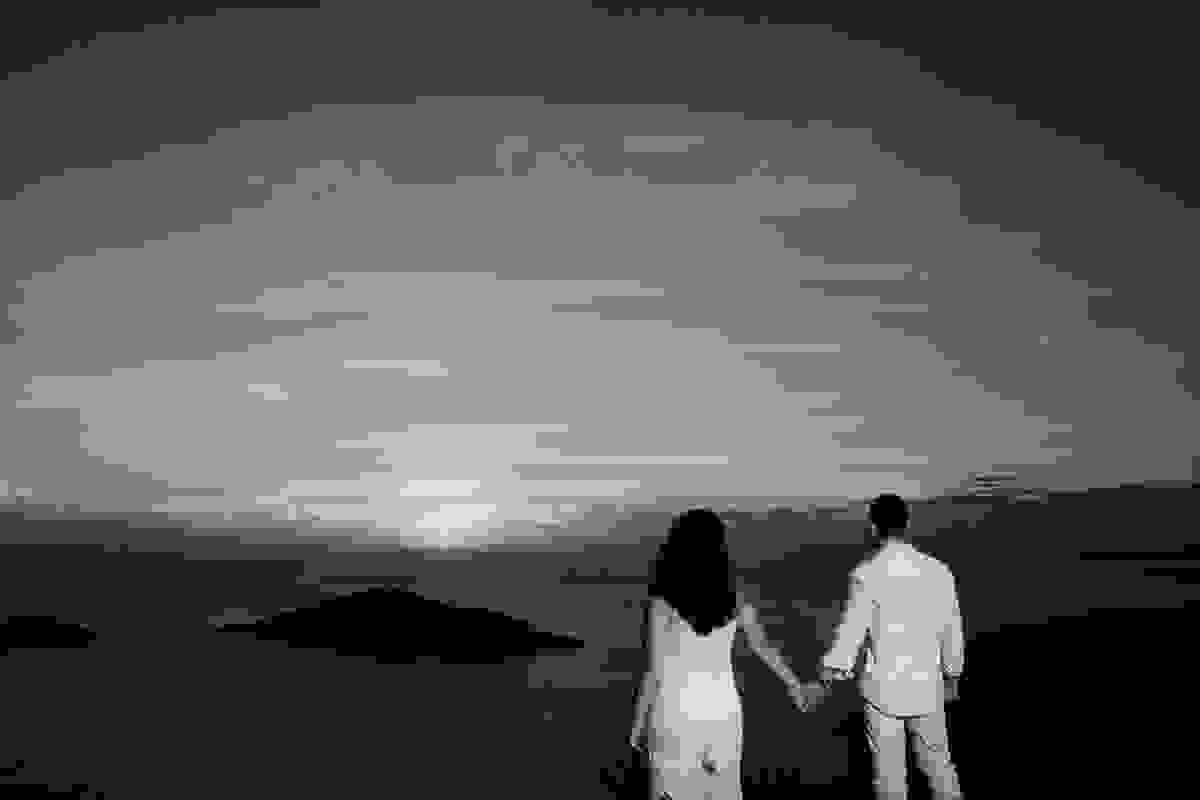 casal de mãos dadas olhando o por do sol de arraial do cabo em fotografia de ensaio pós casamento