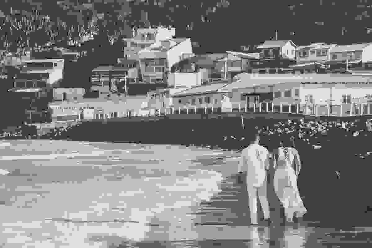 Casal caminha pela praia dos anjos em arraial do cabo rio de janeiro em fotografia do ensaio de lua de mel