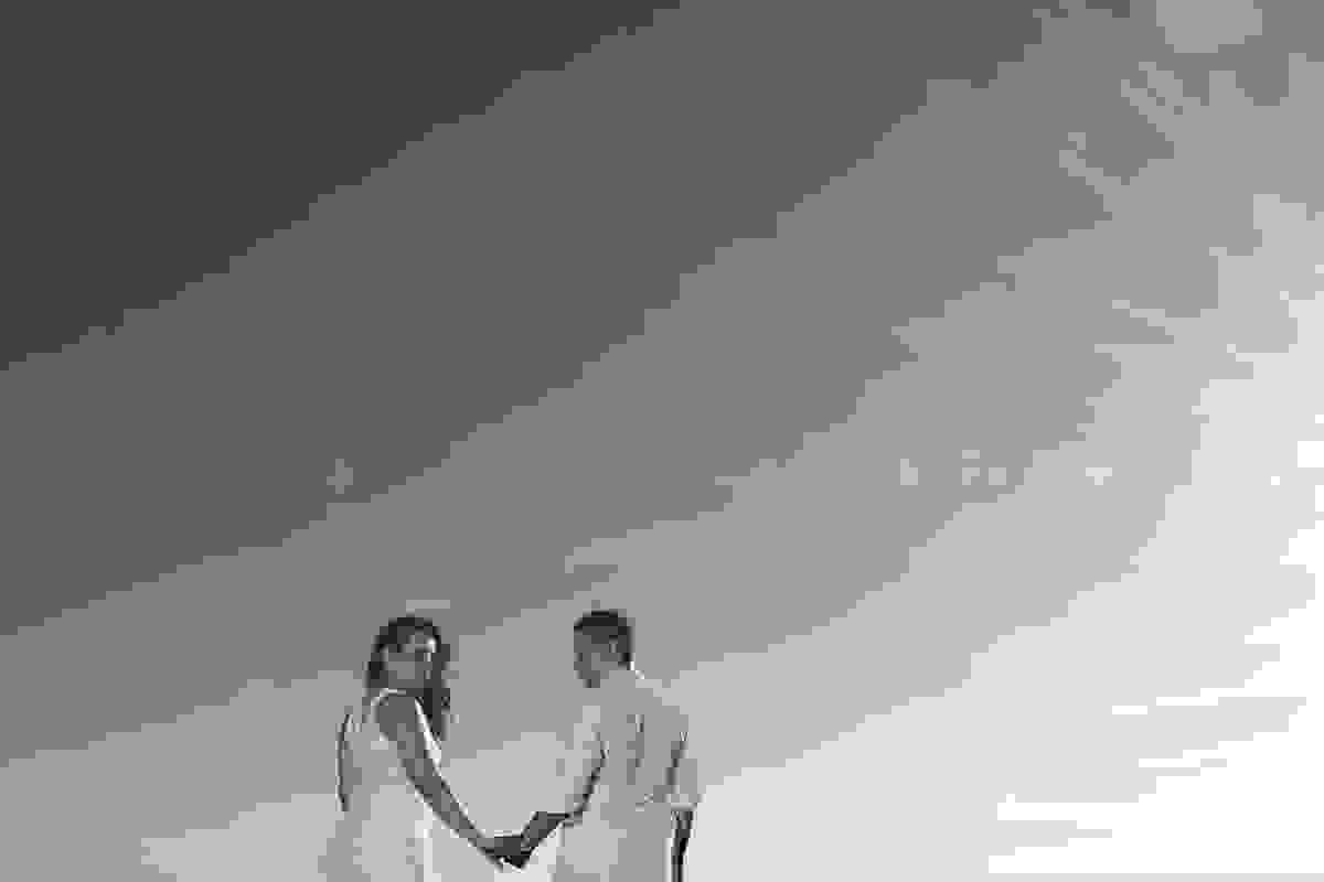 fotografia pos casamento mostra o casal de costa olhando para traz em uma bela imagem do ceu de arraial do cabo e no canto da foto um raio de sol