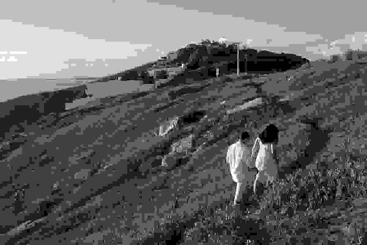 casal caminha por uma trilha no alto do atalaia em arraial do cabo uma das mais belas vistas do brasil