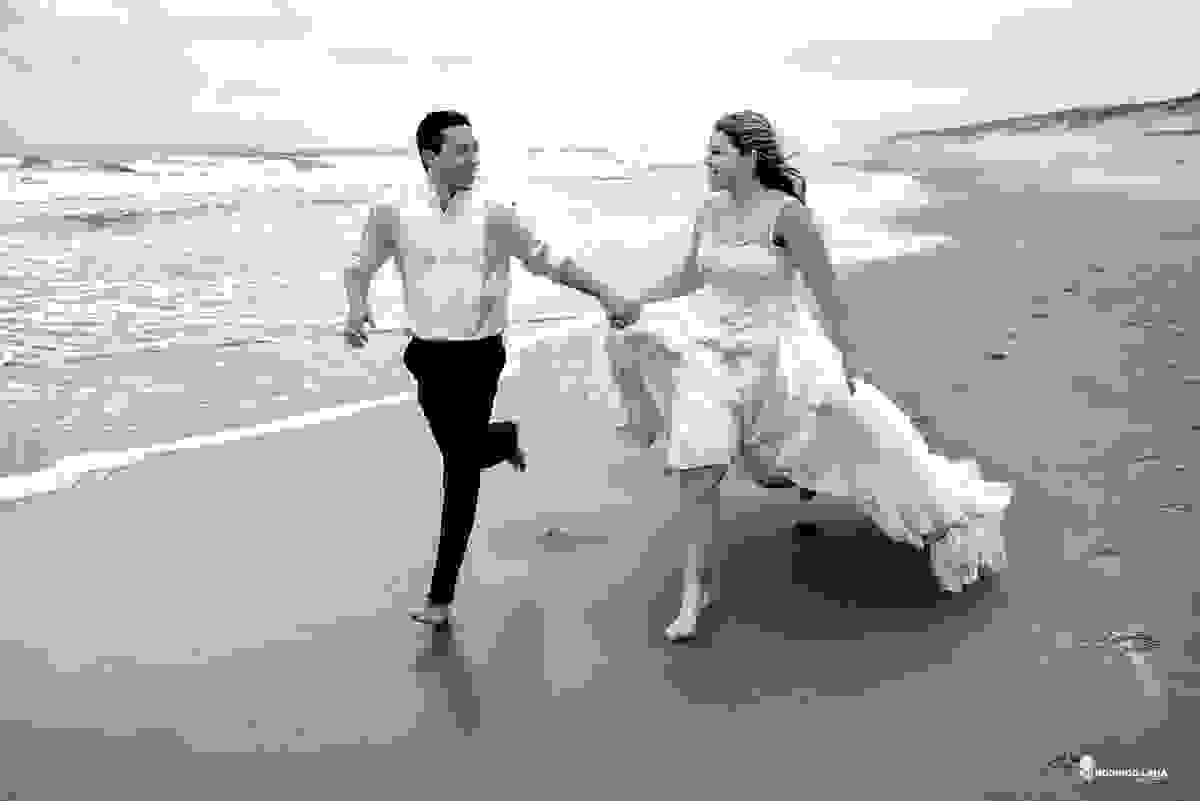 noiva e noivo correndo felizes juntos no ensaio na praia