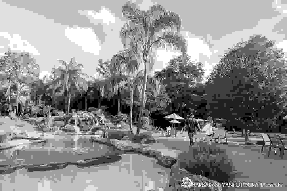 Noivo e noiva caminhando ao lado da piscina natural com lindo céu azul no click da fotógrafa de casamento Minas Gerais MG Bárbara Suyan no Hotel Ville Real em Ouro Preto com muito amor