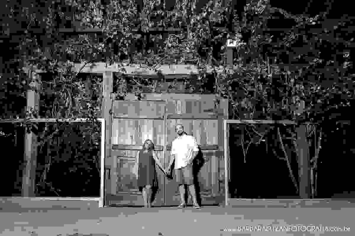Noivo e noiva de mãos dadas na porta de madeira com flores no click da fotógrafa de casamento Minas Gerais MG Bárbara Suyan no Hotel Ville Real em Ouro Preto com muito amor