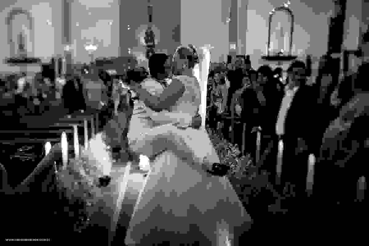 noivo beijando a noiva empolgado colocando uma das pernas atrás dela na igerja no click do fotógrafo de casamento em salvador BA Sandro Andrade numa cena engraçada em preto e branco