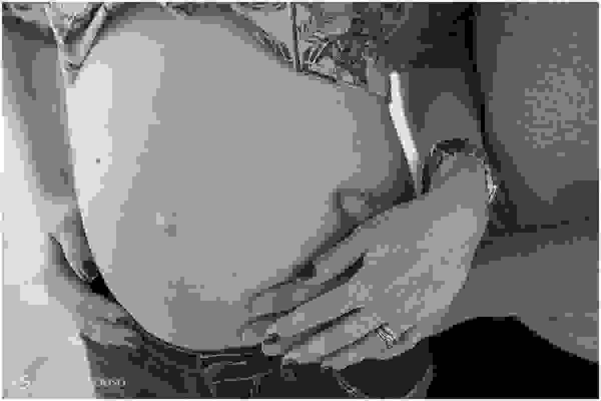 Close na barriga e nas mãos do casal de grávidos